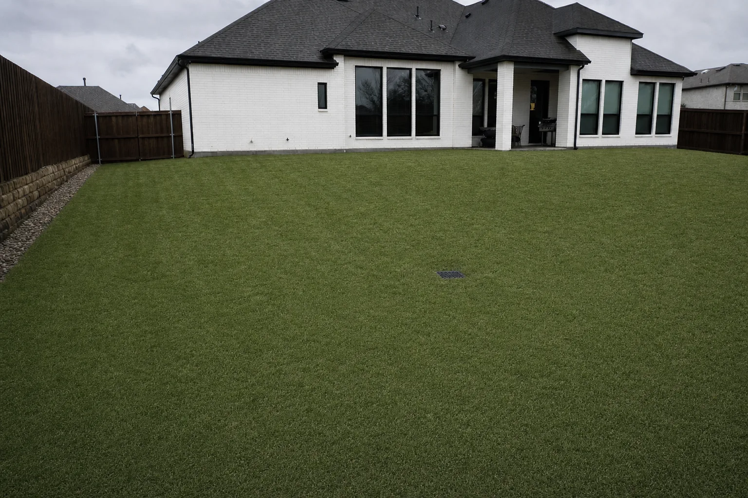 The same backyard fully drained with healthy turf and a flush catch basin